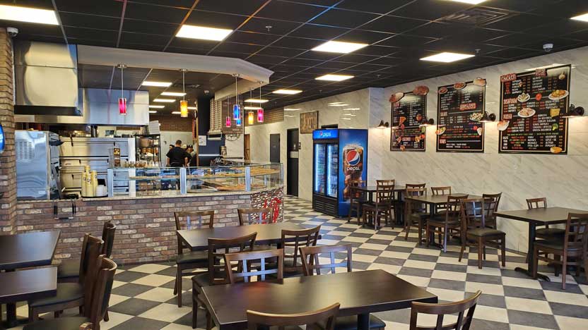 View of the interior of Anthony Franocos brightly lit dining area with checkered floors and plenty of tables to sit an enjoy some delicious pizza.