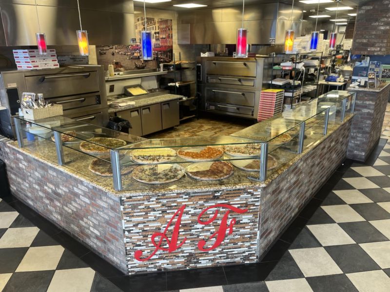 Inside Anthony Franco's Pizza in Roxbury, NJ, featuring a counter and countertop displaying a variety of fresh pizzas.